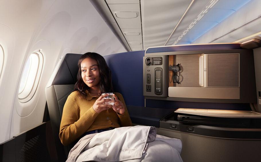A woman holding a cup and looking outside on her business class seat.